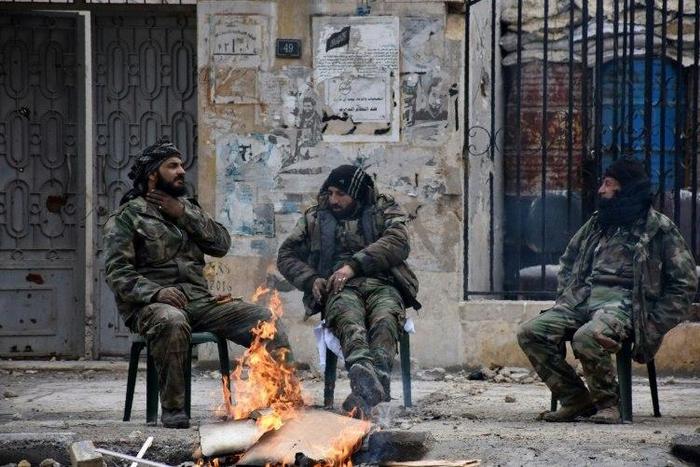 Syrians soldiers sit by a fire in the former rebel-held Ansari district of Aleppo, on December 23, 2016