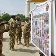 Soldiers take pictures of a banner with the Nigerian army's list of most wanted Boko Haram Islamists, in Maiduguri, on November 21, 2016