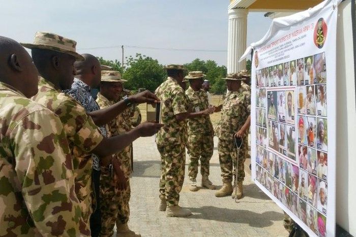 Soldiers look at the Nigerian army's latest list of most wanted Boko Haram members in Maiduguri, northeast Nigeria, on November 21, 2016