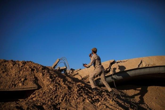 An Iraqi militia member checks the position of an Islamic State sniper at Tal Afar airport