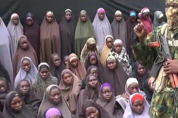 This video grab image created on August 14, 2016 taken from a video released on Youtube purportedly by Boko Haram showing what is claimed to be one of the groups fighters at an undisclosed location standing in front of alleged Chinok Girls 