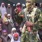 This video grab image created on August 14, 2016 taken from a video released on Youtube purportedly by Boko Haram showing what is claimed to be one of the groups fighters at an undisclosed location standing in front of alleged Chinok Girls 