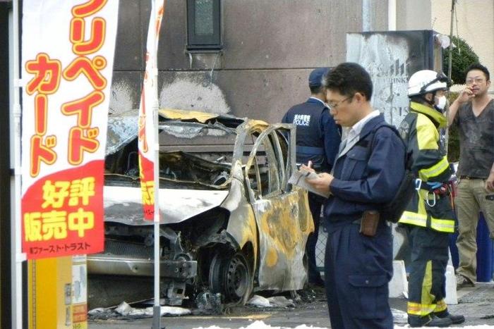 Policemen and firefighters investigate a parking lot after an explosion in Utsunomiya killed one person and at least two injured on October 23, 2016