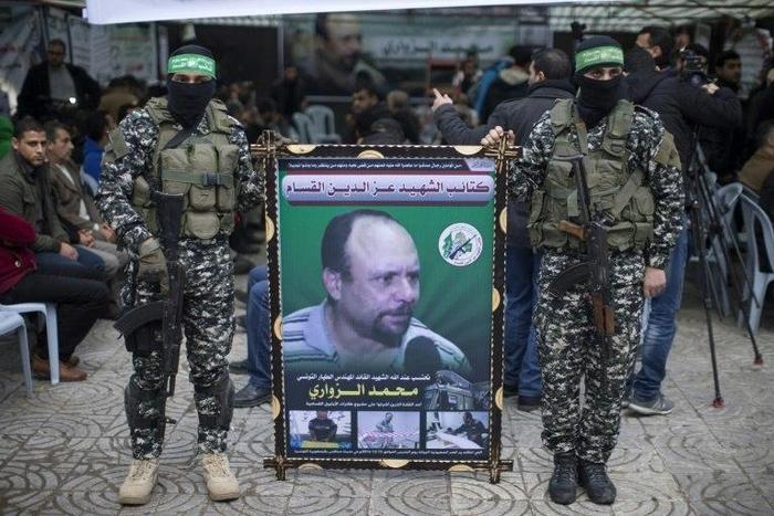 Members of the Ezzedine al-Qassam Brigades, the military wing of the Palestinian Islamist movement Hamas, hold a banner bearing a portrait of one of their leaders, Mohamed Zaouari, who was murdered in Tunisia, during a ceremony in his memory