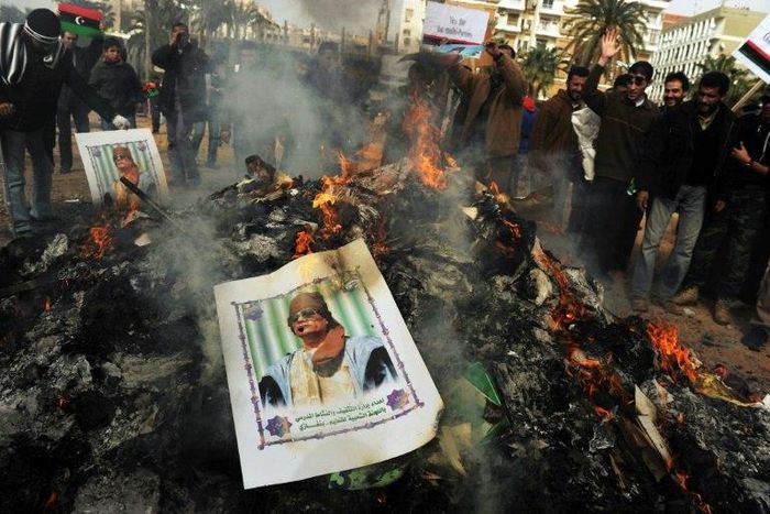 A portrait of Libyan strongman Moamer Kadhafi burns ontop of a pile of ashes accumulated after hundreds of copies of his "green book" were burned in Benghazi on March 02, 2011