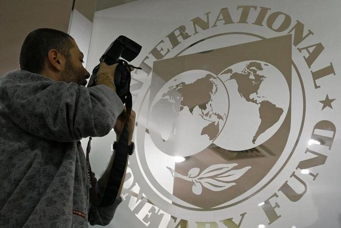 A photographer takes pictures through a glass carrying the International Monetary Fund (IMF) logo during a news conference in Bucharest , file.