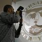 A photographer takes pictures through a glass carrying the International Monetary Fund (IMF) logo during a news conference in Bucharest , file.