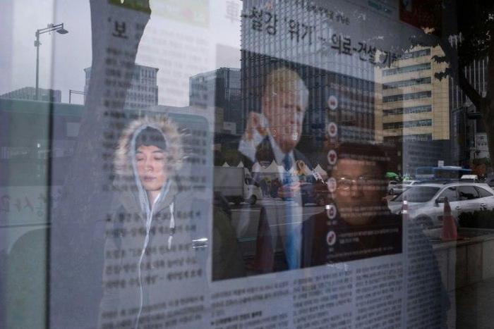 A man looks at a newspaper displaying an image of Donald Trump and coverage of the US presidential elections, in Seoul