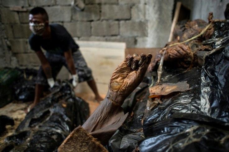 A worker arranges bodies in various stages of decomposition at the morgue of Henry's Funeral Homes in Manila