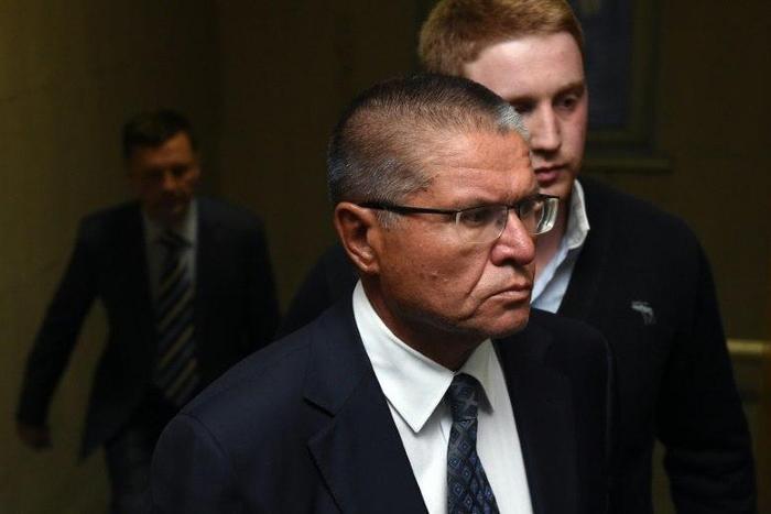 Russia's Economy Minister Alexei Ulyukayev, charged by the Investigative Committee with bribe-taking, is escorted before a hearing at the Basmanny district court in Moscow on November 15, 2016