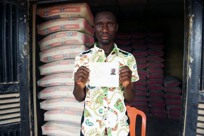 Mike Esorae displays document that denied his stay in France at his cement shop, Idogbo village, in midwest Nigeria, on October 21, 2016