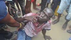 The robbery suspect has been soaked in blood from heavy beating by the mob.