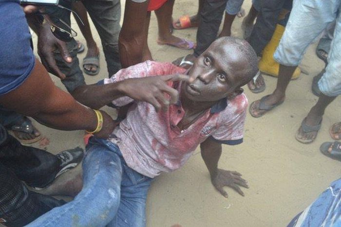 The robbery suspect has been soaked in blood from heavy beating by the mob.