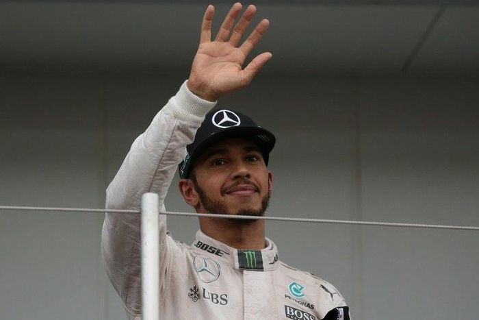 Third-placed Mercedes AMG Petronas F1 Team's British driver Lewis Hamilton waves from the podium after the Formula One Japanese Grand Prix, at the Suzuka Circuit, on October 9, 2016