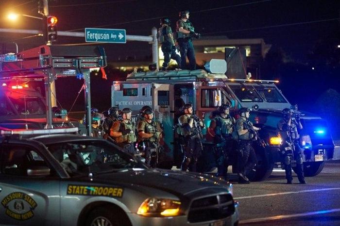 St. Louis County Police officers, outfitted in tactical equipment, monitor the situation in Ferguson, Missouri on August 10, 2015