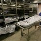 Morgue attendant is seen pushing a corpse lying on a gurney,