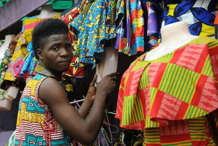 A tailor prepares clothes to sell at an African clothes shop in Monrovia