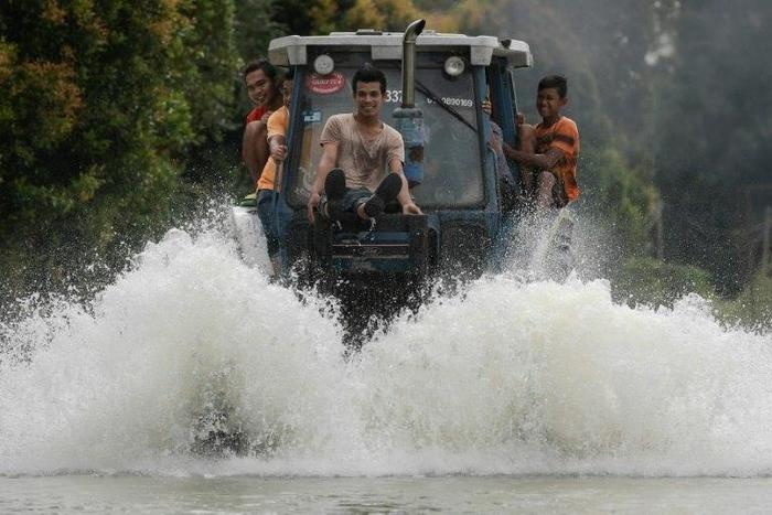 Local residents use a tractor to drive through floodwaters in Jal Besar, in the northeastern Malaysian town of Tumpat on January 5, 2017
