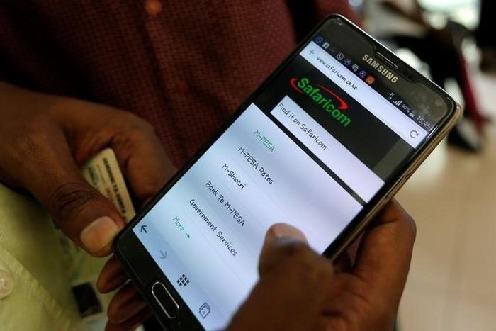 An employee assists a customer to set-up M-Pesa money transfer servive on his handset inside a mobile phone care centre operated by Kenyan's telecom operator Safaricom; in the central business district of Kenya's capital Nairobi, May 11, 2016. REUTERS/...