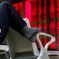 An investor puts his feet on a chair in front of an electronic board showing stock information at a brokerage house in Beijing, China, February 16, 2016.
