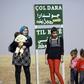 A Kurdish woman and her children stand by a sign for the village of Joldara (meaning plain covered in trees) and known as Shajra in Arabic, near the northeastern Syrian city of Qamishli on October 3, 2016