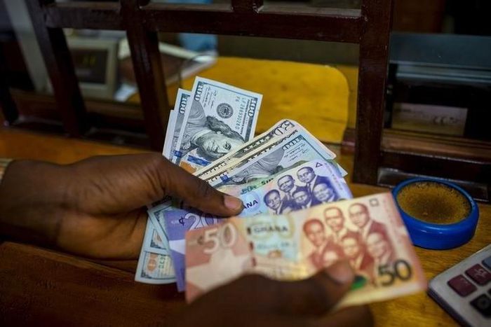 A man trades U.S. dollars for Ghanaian cedis at a currency exchange office in Accra, Ghana, June 15, 2015. Picture taken June 15. REUTERS/Francis Kokoroko