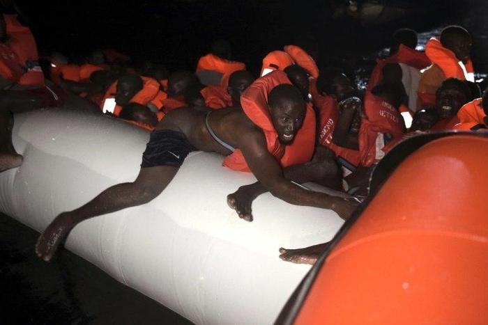 Refugees and migrant wait to be rescued as their rubber boat sinks some eight nautical miles off Libya's Mediterranean coastline