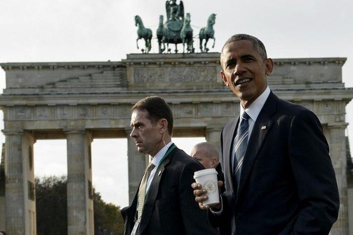 US President Barack Obama (R) passes the Brandenburg Gate in Berlin while walking from the US Embassy to the Adlon Hotel on November 17, 2016