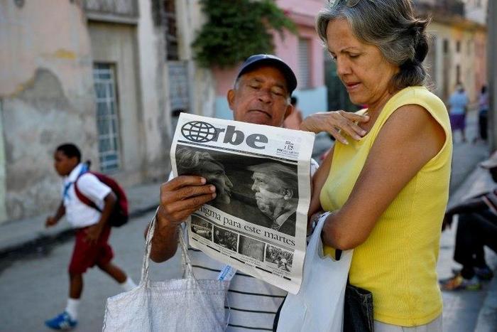 Cubans read a newspaper with its front page informing of the victory of US presidential candidate Donal Trump in a street of Havana, on November 9, 2016