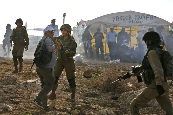 An Israeli soldier scuffles with a Palestinian journalist during a demonstration against the construction of Jewish settlements in the West Bank