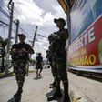 Filipino soldiers stand guard next to a poster of Philippine President Rodrigo Duterte.
