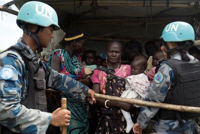 United Nations peacekeepers control South Sudanese women and children before the distribution of emergency food supplies at the United Nations protection of civilians (POC) site 3 hosting about 30,000 people displaced during the recent fighting in Juba...