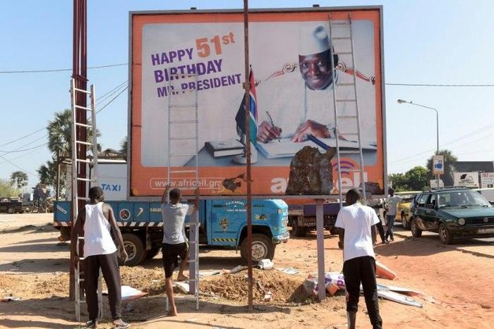 Workers prepare to remove an electoral poster for longtime Gambian leader Yahya Jammeh, after he conceded defeat in a presidential poll
