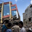 People walk past a collapsed building after a fresh 7.3 earthquake struck, in Kathmandu, Nepal, May 12, 2015.     REUTERS/Athit Perawongmetha