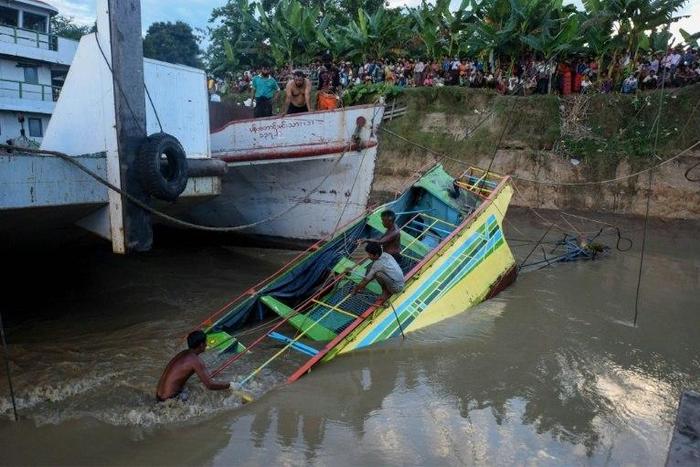 Rescue workers stand on the partly sunken ferry that capsized on the Chindwin River killing nearly 50 people four days ago