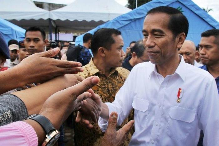 Indonesian President Joko Widodo shakes hands with quake survivors at a temporary shelter in Pidie Jaya, Aceh province