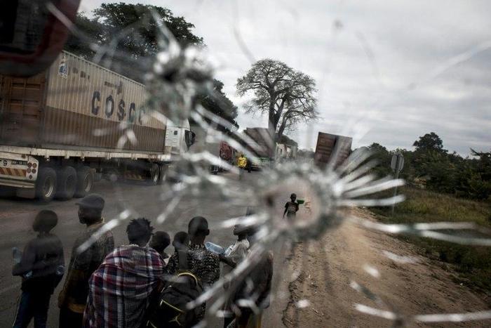 Street vendors are seen through a bullet hole in a bus windscreen in the Gorongosa area of Mozambique on May 27, 2016