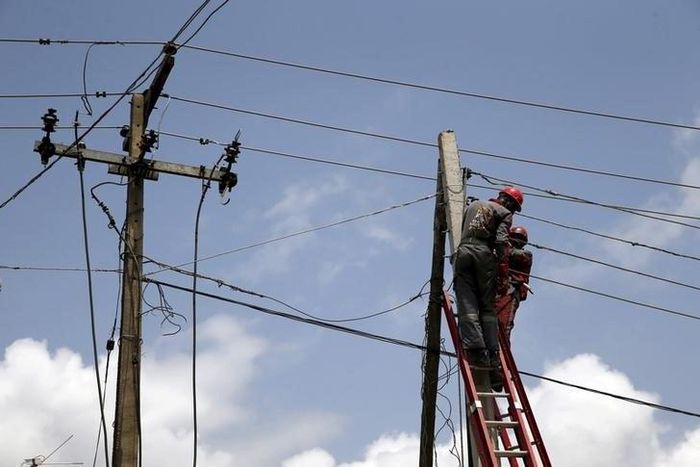 Power officials stand on ladders to fix electric cables along a road in Egbeda dstrict in Nigeria's commercial capital Lagos, July 1, 2015. Picture taken July 1, 2015. REUTERS/Akintunde Akinleye