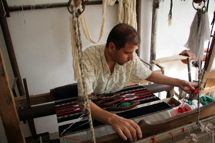Syrian weaver Abu Ahmed works his loom on the last day before the workshop is forced to close due to a lack of thread imported from conflict-ridden Aleppo
