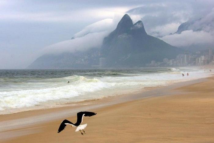 A seagul flies over Ipanema beach on a cloudy day in Rio de Janeiro