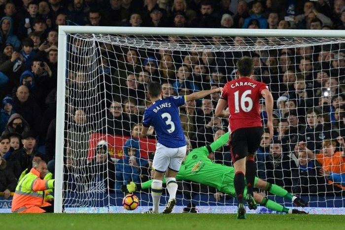 Everton's defender Leighton Baines (L) scores his penalty past the diving Manchester United's goalkeeper David de Gea during the English Premier League football match between Everton and Manchester United at Goodison Park on December 4, 2016