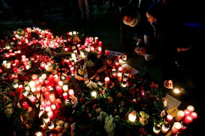 People light candles at a makeshift memorial in front of the Kaiser-Wilhelm-Gedaechtniskirche in Berlin, where a truck crashed the day before into a Christmas market