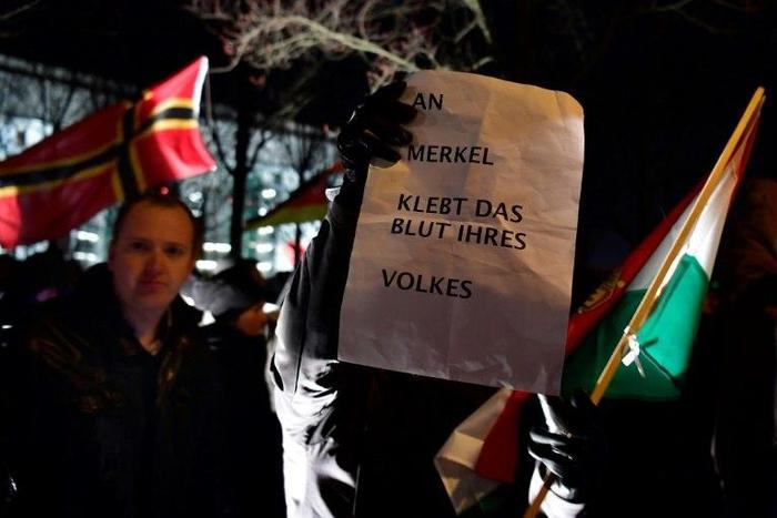 Supporters of German populist party AfD hold a placard reading 'Merkel has blood of her nation on her hands' during a prostest rally in Berlin