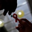 A nurse (L) hands out a red ribbon to a woman, to mark World Aids Day, at the entrance of Emilio Ribas Hospital, in Sao Paulo December 1, 2014.