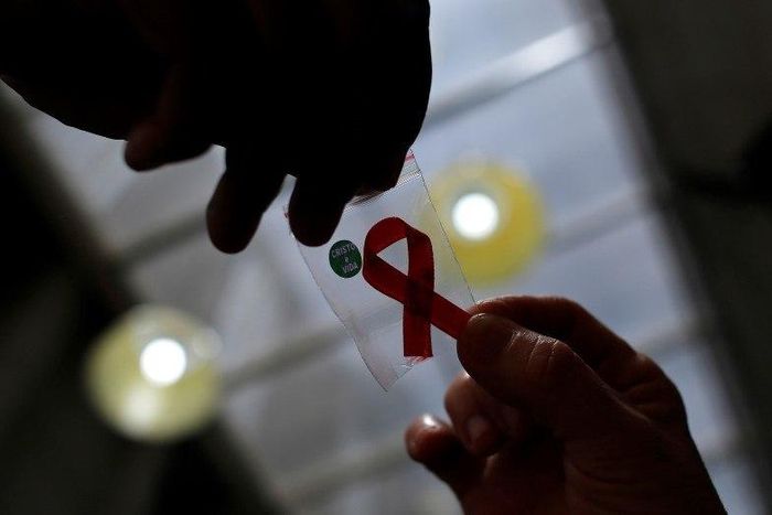 A nurse (L) hands out a red ribbon to a woman, to mark World Aids Day, at the entrance of Emilio Ribas Hospital, in Sao Paulo December 1, 2014.