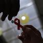 A nurse (L) hands out a red ribbon to a woman, to mark World Aids Day, at the entrance of Emilio Ribas Hospital, in Sao Paulo December 1, 2014. REUTERS/Nacho Doce