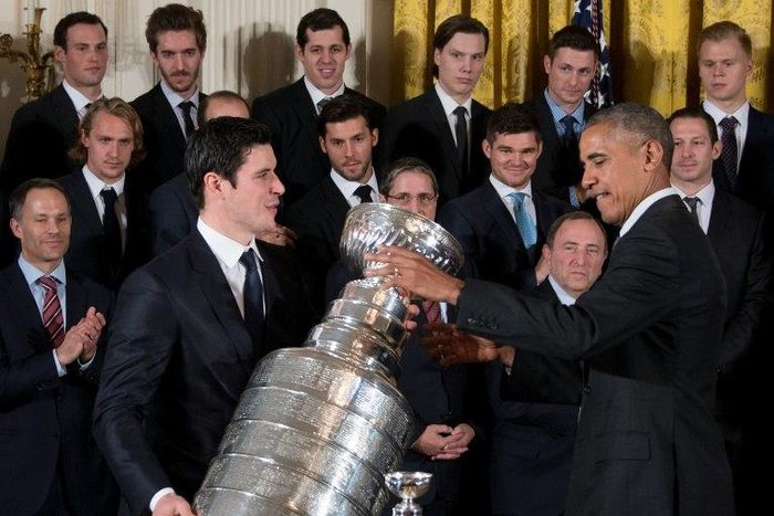 US President Barack Obama (R) gestures as Pittsburgh Penguins captain Sidney Crosby (L) picks up the Stanley Cup during an event at the White House in Washington, DC, October 6, 2016, honoring the Penguins 2016 Stanley Cup victory