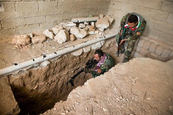 A Peshmerga fighter fires a warning shot into an Islamic State tunnel in Bashiqa on November 9, 2016