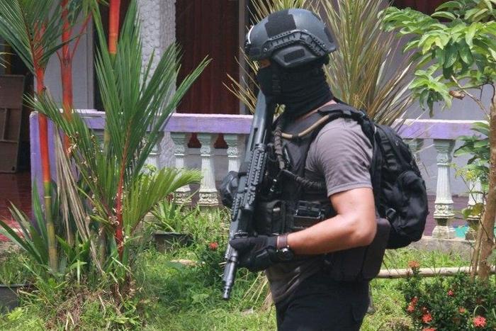 An Indonesian anti-terror police officer patrols the grounds of a house after a firefight erupted in South Tangerang, near Jakarta, on December 21, 2016
