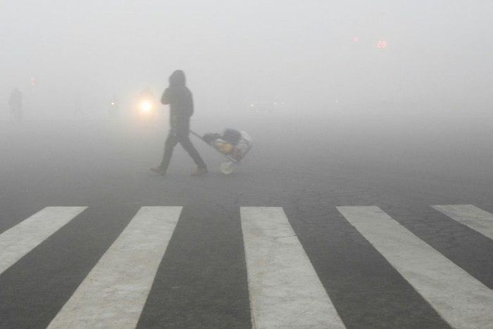 A pedestrian crosses a smog-shrouded street in Lianyungang, eastern China's Jiangsu province on December 19, 2016